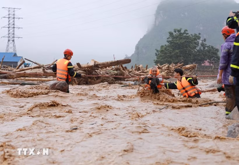 Lực lượng cứu nạn cứu hộ Công an tỉnh Lai Châu căng dây giữa dòng nước lũ đưa người dân xã Mường Than ra khỏi vùng bị cô lập nguy hiểm đến nơi ở an toàn. (Ảnh: Quý Trung/TTXVN)