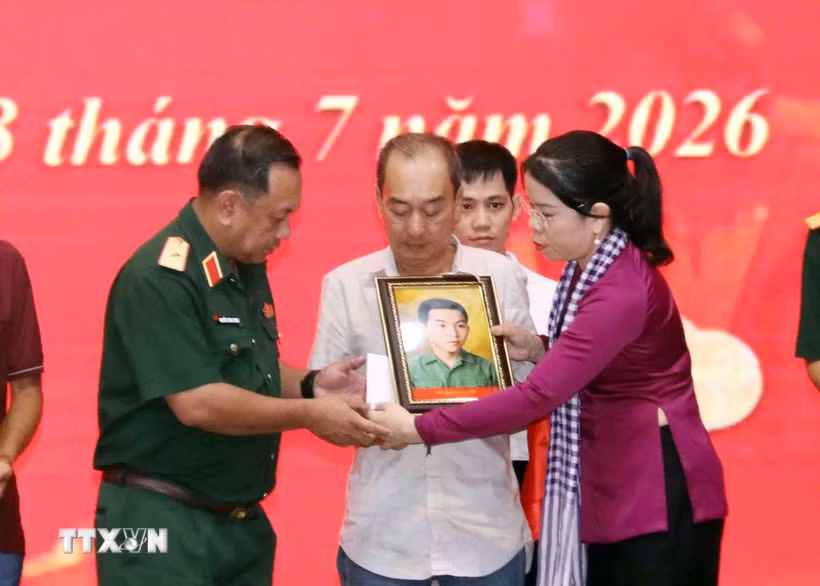Phút nghẹn ngào của thân nhân liệt sỹ đón nhận di ảnh liệt sỹ đã được phục dựng. (Ảnh: Xuân Khu/TTXVN)