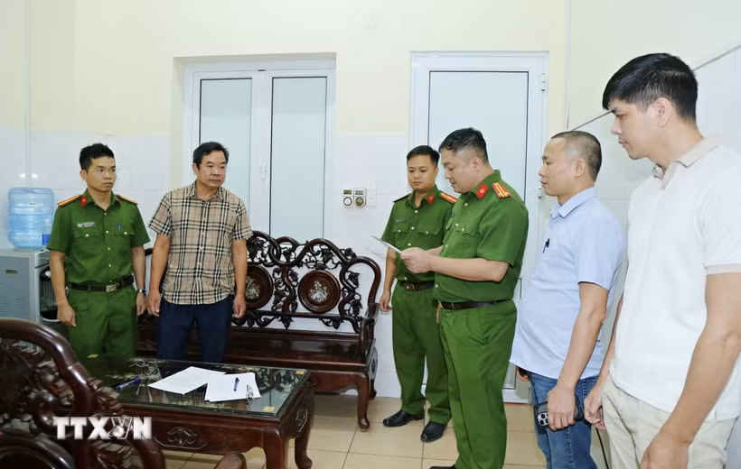 Cơ quan Cảnh sát điều tra, Công an tỉnh khám xét nơi làm việc của Hoàng Văn Huấn (áo kẻ). (Ảnh: TTXVN phát)