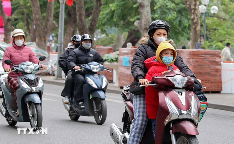 Người dân mặc áo khoác dáng dài và quàng khăn ấm khi di chuyển bằng xe máy qua khu vực hồ Hoàn Kiếm. (Ảnh: Vũ Quang/TTXVN)