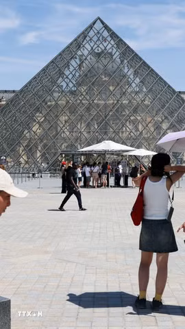 Du khách tham quan Bảo tàng Louvre ở Paris, Pháp dưới trời nắng gay gắt. (Ảnh: THX/TTXVN phát)