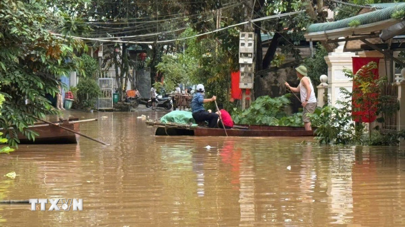 Người dân phải dùng thuyền để làm phương tiện di chuyển trong những ngày mưa lũ. (Ảnh: Việt Hoàng/TTXVN)
