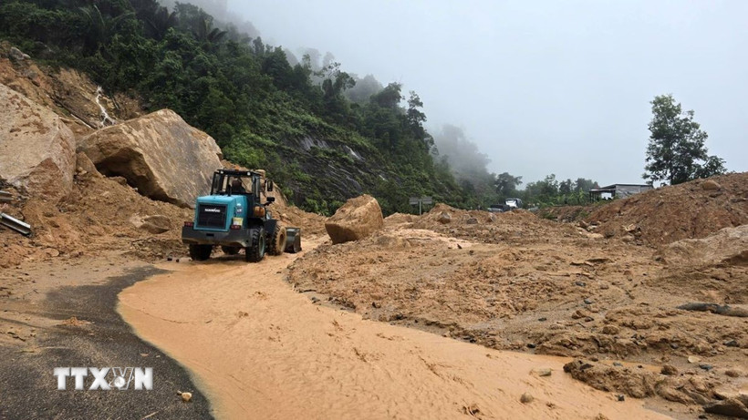 Lực lượng chức năng tỉnh Khánh Hòa huy động thiết bị cơ giới dọn dẹp đất đá bị sạt lở để tiếp cận hiện trường đưa nạn nhân ra ngoài. (Ảnh: Đặng Tuấn/TTXVN)