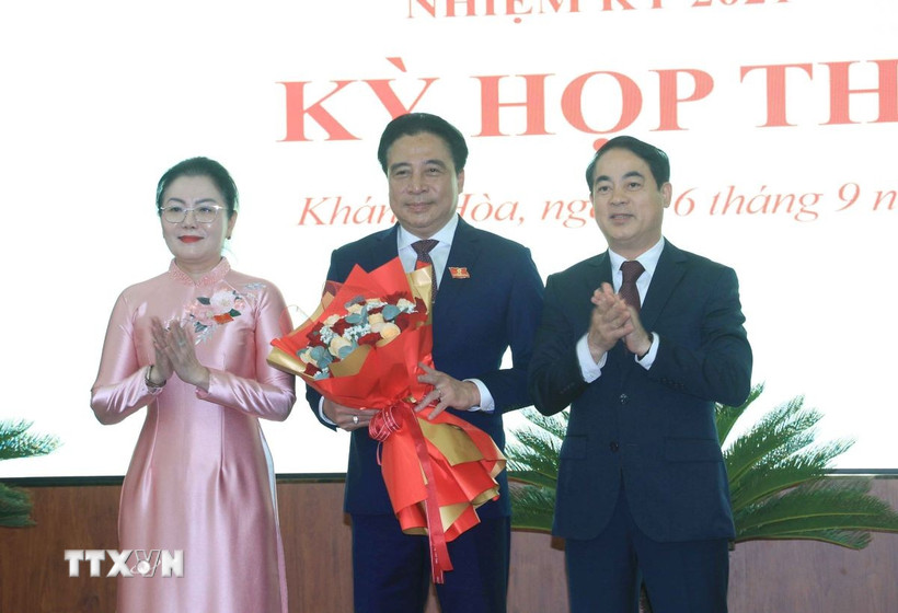 Ông Nghiêm Xuân Thành (phải), Bí thư Tỉnh ủy và bà Phạm Thị Xuân Trang, Phó Chủ tịch HĐND tỉnh Khánh Hòa tặng hoa chúc mừng ông Nguyễn Khắc Toàn được bầu giữ chức Chủ tịch UBND tỉnh Khánh Hòa nhiệm kỳ 2021-2026. (Ảnh: Phan Sáu/TTXVN)