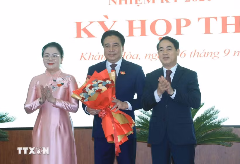 Ông Nghiêm Xuân Thành (phải), Bí thư Tỉnh ủy và bà Phạm Thị Xuân Trang, Phó Chủ tịch HĐND tỉnh Khánh Hòa tặng hoa chúc mừng ông Nguyễn Khắc Toàn được bầu giữ chức Chủ tịch UBND tỉnh Khánh Hòa nhiệm kỳ 2021-2026. (Ảnh: Phan Sáu/TTXVN)