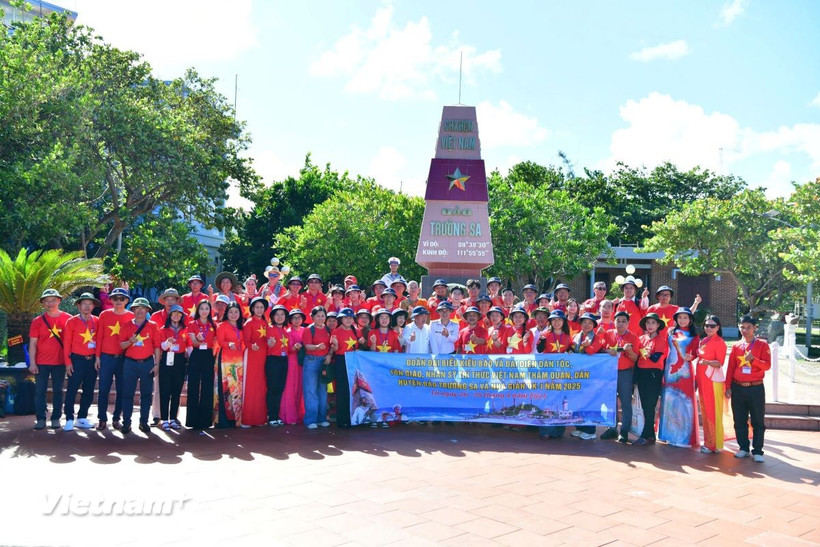 Các đại biểu chụp ảnh lưu niệm tại Cột mốc chủ quyền tại đảo Trường Sa. (Ảnh: Vietnam+)