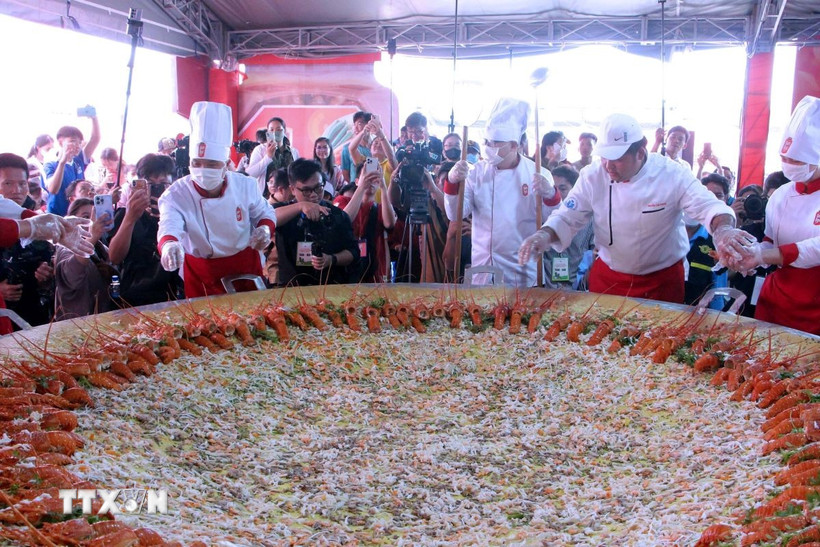 Các nghệ nhân trình diễn đổ chiếc bánh xèo khổng lồ có 100 con tôm hùm trong khuôn khổ Lễ hội. (Ảnh: Trung Kiên/TTXVN)