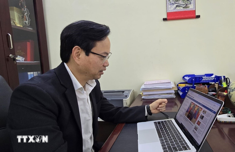 Tiến sỹ Nguyễn Đình Hoàng nghiên cứu thông tin về Đại hội Đại biểu toàn quốc lần thứ XIV của đảng trên website của Thông tấn xã Việt Nam. (Ảnh: Minh Thu/TTXVN)