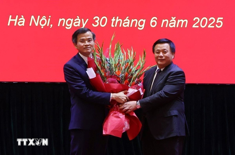 Ủy viên Bộ Chính trị, Giám đốc Học viện Chính trị quốc gia Hồ Chí Minh, Chủ tịch Hội đồng Lý luận Trung ương Nguyễn Xuân Thắng trao Quyết định và tặng hoa chúc mừng ông Đoàn Minh Huấn. (Ảnh: Văn Điệp/TTXVN)