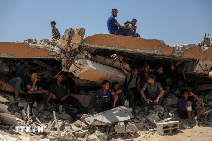 Người dân Palestine ngồi trên đống đổ nát ở khu vực Sudaniya, phía Bắc thành phố Gaza. (Ảnh: THX/TTXVN)