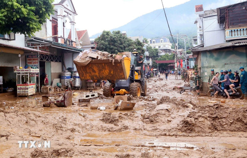 Máy xúc được huy động để hỗ trợ san gạt, thu gom bùn đất, cành cây, rác bị tràn về trong đợt lũ vừa qua tại xã Sông Mã. (Ảnh: Quang Quyết/TTXVN)