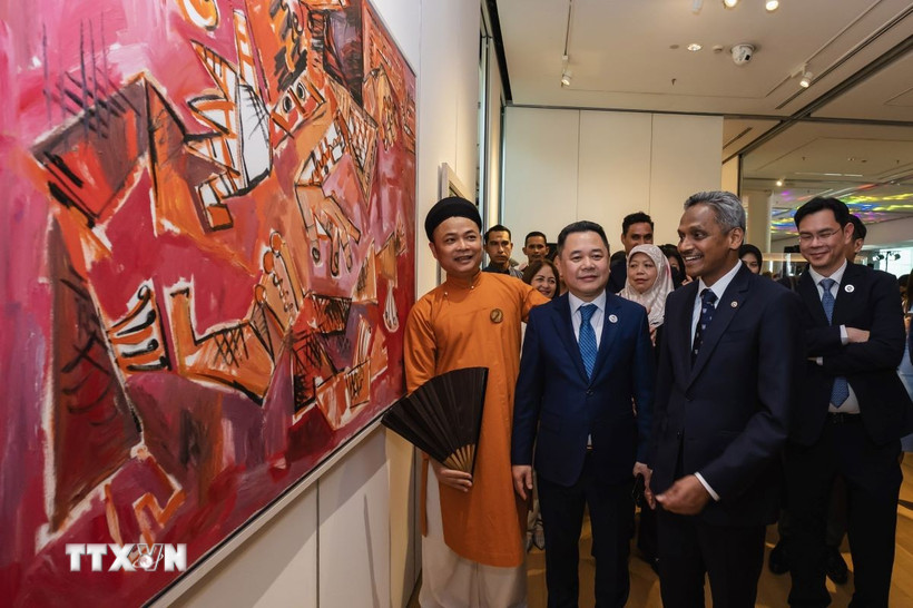 Họa sỹ Nguyễn Tuấn Sơn (trái) thuyết trình về tác phẩm của mình trước Phó Thống đốc Ngân hàng Nhà nước Việt Nam Nguyễn Ngọc Cảnh (giữa) và Thống đốc Ngân hàng Trung ương Malaysia Shaik Abdul Rasheed bin Abdul Ghaffour (phải). (Ảnh: Hằng Linh/TTXVN)