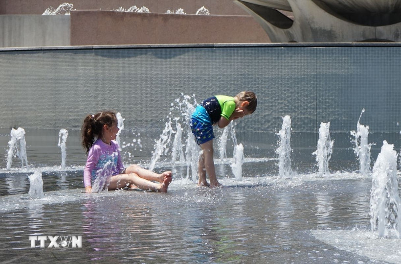 Trẻ em giải nhiệt tránh nóng tại một đài phun nước. (Ảnh: THX/TTXVN)
