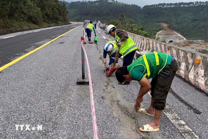 Lực lượng công nhân tiến hành nhồi sợi dây đay vào khe nứt rồi đổ nhựa đường nhằm ngăn nước thấm xuống phía dưới tại sự cố nứt đường trên Quốc lộ 1A, đoạn qua Đèo Ngang. (Ảnh: TTXVN phát)
