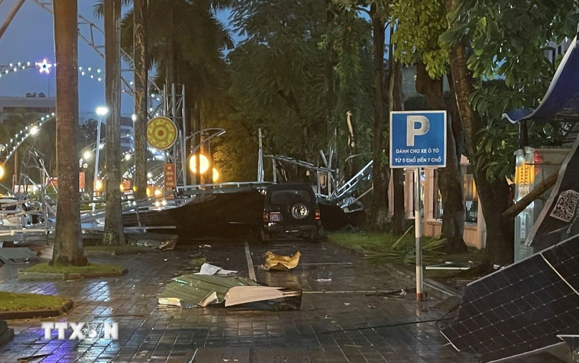 Biển bảng quảng cáo đổ sập lên xe ôtô đang đậu trên vỉa hè. (Ảnh: TTXVN phát)