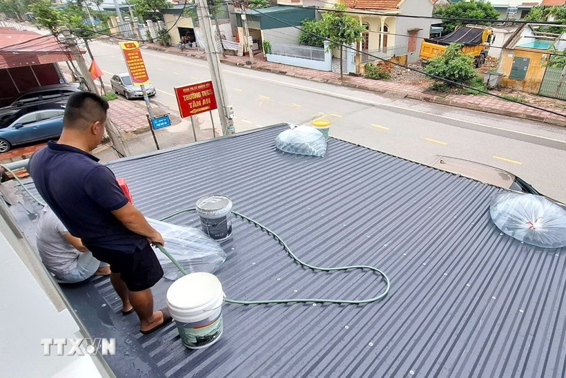 Người dân phường Hà An, tỉnh Quảng Ninh dùng các bao nước để gia cố mái tôn. (Ảnh: Đức Hiếu/TTXVN)
