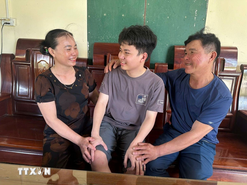 Em Trần Công Nguyên, học sinh lớp 12 Hóa, trường THPT Chuyên Hà Tĩnh, thủ khoa khối A00 chia sẻ niềm vui cùng bố mẹ sau khi biết điểm thi tốt nghiệp THPT năm 2025. (Ảnh: TTXVN phát)