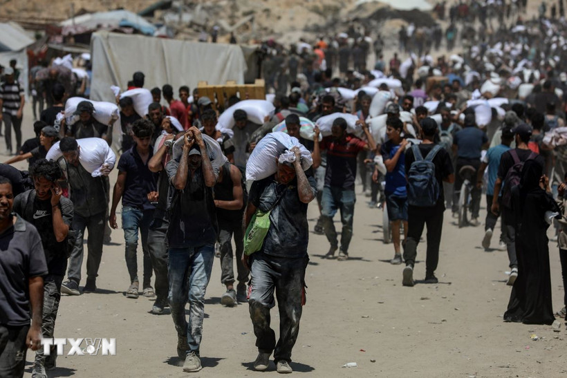 Israel phát hiện nhiều hàng cấm trong các xe chở hàng cứu trợ vào Gaza Người dân Palestine nhận hàng viện trợ nhân đạo. (Ảnh: THX/TTXVN)