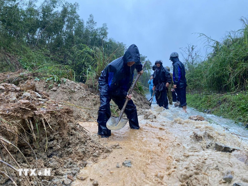 Các lực lượng đào, vét đất đá, mở rãnh thoát nước và thu dọn bùn đất tràn xuống mặt đường, tạo lối đi tạm để phương tiện qua lại. (Ảnh: TTXVN phát)