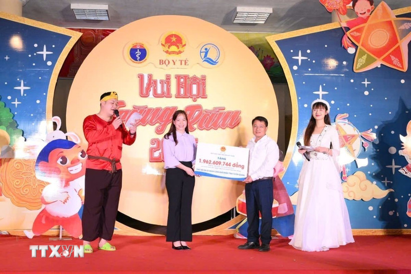 Bà Nguyễn Thị Hiền - Phó Giám đốc Quỹ Bảo trợ trẻ em Việt Nam trao biển tượng trưng tặng quà cho trẻ em có hoàn cảnh khó khăn tỉnh Tuyên Quang. (Ảnh: TTXVN phát)