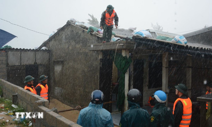 Các cán bộ chiến sỹ Bộ đội Biên phòng bất chất mưa gió, nguy hiểm tích cực hỗ trợ người dân sống ven biển chằng chống nhà cửa. (Ảnh: Văn Dũng/TTXVN)