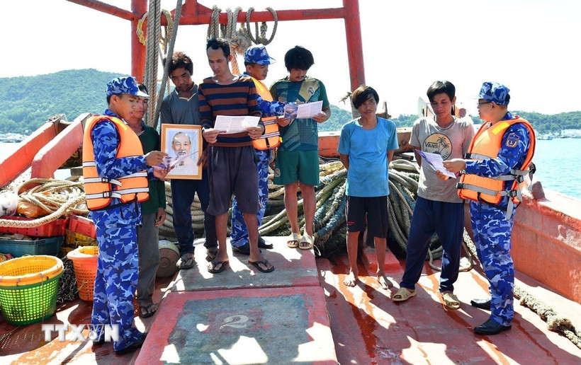 Vùng Cảnh sát biển 4 tặng cờ Tổ quốc, ảnh Bác Hồ cho ngư dân và phát tờ rơi tuyên truyền về khai thác IUU. (Ảnh: TTXVN phát)