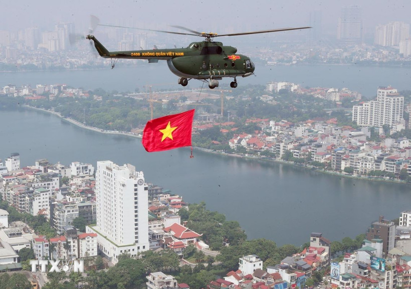 Biên đội máy bay trực thăng của Quân chủng Phòng không-Không quân treo cờ Đảng và cờ Tổ quốc bay vào khu vực trung tâm Thủ đô Hà Nội. (Ảnh: Trọng Đức/TTXVN)
