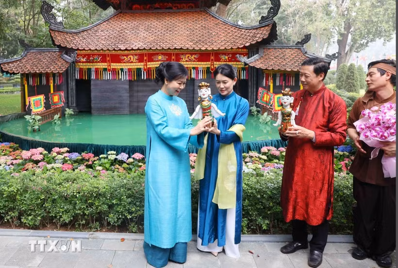 Bà Ngô Phương Ly, Phu nhân Tổng Bí thư Tô Lâm tặng con rối nước cho bà Loo Tze Lui, Phu nhân Thủ tướng Singapore Lawrence Wong. (Ảnh: Phạm Kiên/TTXVN)