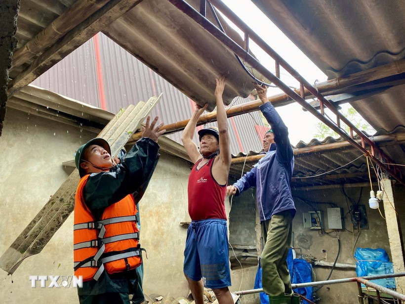 Lực lượng vũ trang hỗ trợ người dân xã Thiên Cầm dọn dẹp nhà cửa hư hỏng do bão. (Ảnh: Hữu Quyết/TTXVN)