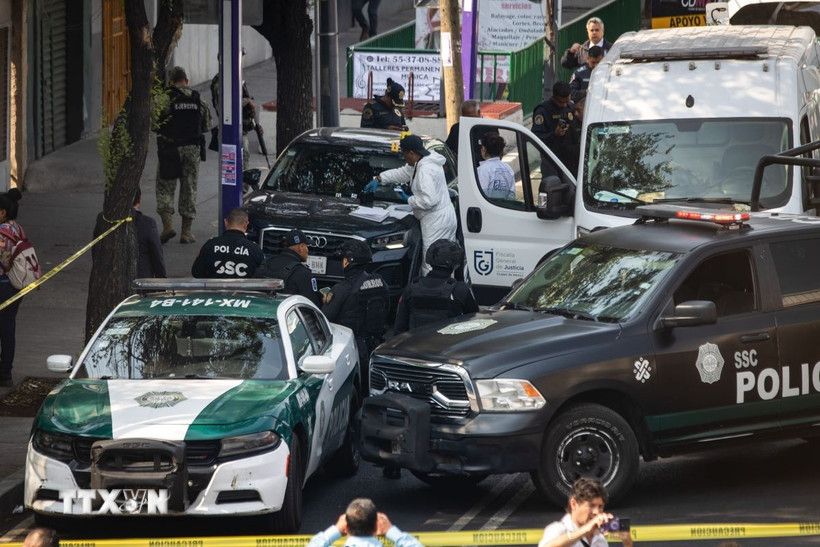 Cảnh sát và nhân viên điều tra làm nhiệm vụ tại hiện trường vụ việc. (Ảnh: THX/TTXVN)