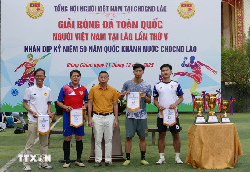 Đại diện Tổng hội người Việt Nam tại Lào trao cờ lưu niệm cho các đội tham dự giải đấu. (Ảnh: Xuân Tú/TTXVN)