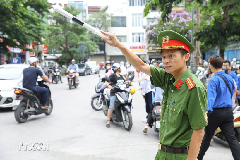 Lực lượng chức năng phân luồng giao thông trước cổng điểm thi THPT Nguyễn Trãi-Ba Đình. (Ảnh: Lê Đông/TTXVN)