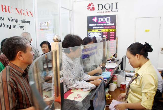 Khách hàng đang giao dịch vàng miếng. (Ảnh: TTXVN) Giá vàng trong nước đi ngang, tỷ giá trung tâm giảm 2 đồng mỗi USD ảnh 1