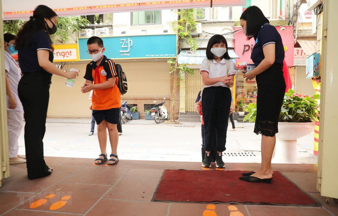 Học sinh được hướng dẫn các biện pháp phòng, chống dịch bệnh khi đến lớp. (Ảnh: TTXVN) Hà Nội chưa chính thức 'chốt' ngày cho học sinh trở lại trường ảnh 1