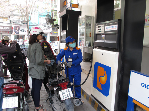 Nhân viên cửa hàng xăng dầu của Petrolimex đang bán xăng cho khách hàng (Ảnh: Đức Duy/Vietnam+) Giá xăng RON 92 tại Petrolimex giảm 550 đồng mỗi lít kể từ 18 giờ ảnh 1