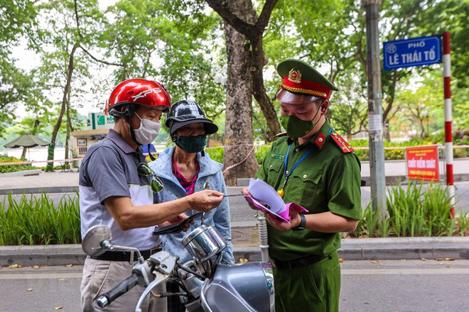 Lực lượng chức năng nhắc nhở người dân thực hiện nghiêm công tác phòng, chống dịch. (Ảnh: Minh Sơn/Vietnam+) Hà Nội hỏa tốc yêu cầu thực hiện nghiêm quy định về giãn cách xã hội ảnh 1