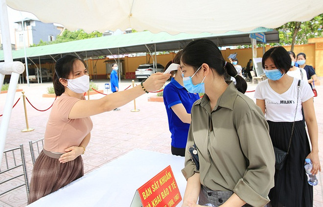 Đo thân nhiệt cho người dân. (Ảnh: PV/Vietnam+) Hà Nội ghi nhận thêm 7 ca dương tính với SARS-CoV-2 từ cộng đồng ảnh 1