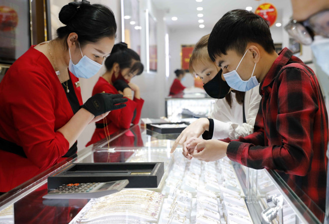 Khách hàng giao dịch vàng miếng. (Ảnh: TTXVN) Đồng loạt đi xuống, giá vàng SJC lùi về ngưỡng 65,2 triệu đồng ảnh 1