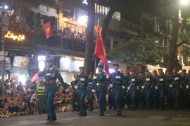 Người dân nô nức vẫy cờ chào đón đoàn diễu hành. (Ảnh: Vietnam+)