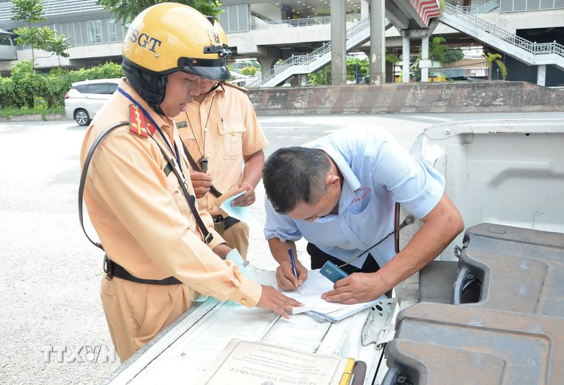 Cảnh sát giao thông lập biên bản một trường hợp tài xế xe khách vi phạm. (Ảnh: Linh Sơn/TTXVN)