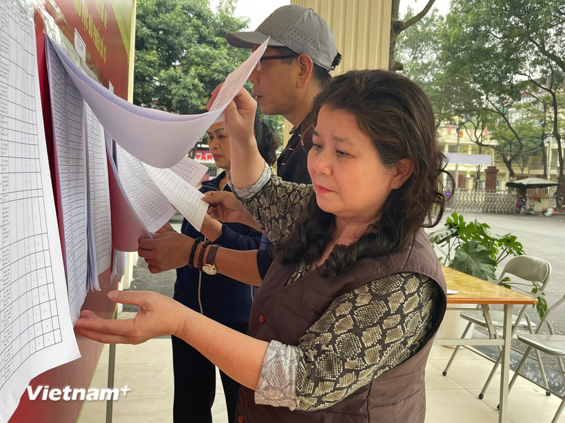 Cử tri phường Từ Liêm kiểm tra danh sách cử tri được niêm yết công khai tại khu vực bỏ phiếu. (Ảnh: Hằng Trần/Vietnam+)