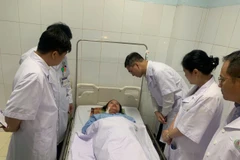 Tiến sỹ Hà Anh Đức - Cục trưởng Cục Quản lý Khám chữa bệnh thăm hỏi, động viên nữ điều dưỡng đang bị thương. (Ảnh: PV/Vietnam+) 