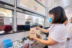 Nhân viên y tế cấp phát thuốc bảo hiểm y tế cho người bệnh. (Ảnh: T.G/Vietnam+)