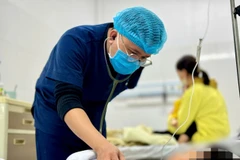 Bác sỹ theo dõi sức khỏe cho một trẻ mắc cúm A. (Ảnh: PV/Vietnam+)