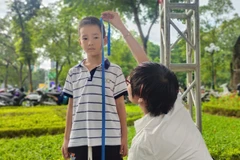 Nhân viên y tế đo chiều cao cho trẻ tại ngày hội. (Ảnh: PV/Vietnam+)