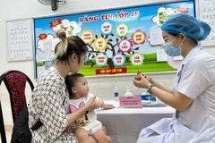 Phụ huynh cho trẻ đến trạm y tế để bổ sung Vitamin A. (Ảnh: PV/Vietnam+)