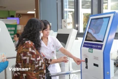 Người bệnh làm thủ tục ở ki-ốt đăng ký khám tự động tại Bệnh viện Đa khoa Đức Giang. (Ảnh: PV/Vietnam+)