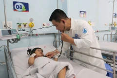 Bác sỹ Bệnh viện Nhi đồng 1 Thành phố Hồ Chí Minh, khám cho bệnh nhi mắc tay chân miệng. (Ảnh: Đinh Hằng/TTXVN)