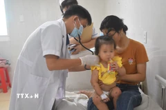 Bác sỹ khám cho bệnh nhân mắc bệnh tay chân miệng. (Ảnh: TTXVN)