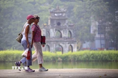 Du khách nước ngoài đi dạo bên hồ Hoàn Kiếm. (Ảnh: Tuấn Đức/TTXVN)